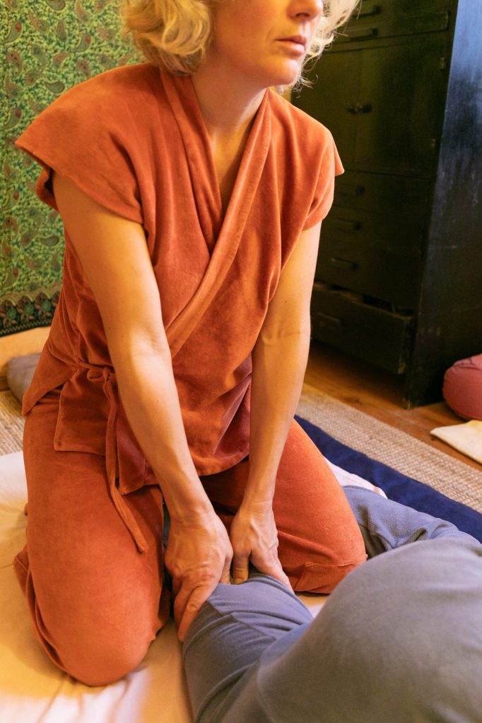 Alice Rigot agenouillée près d’une personne pendant une séance de shiatsu